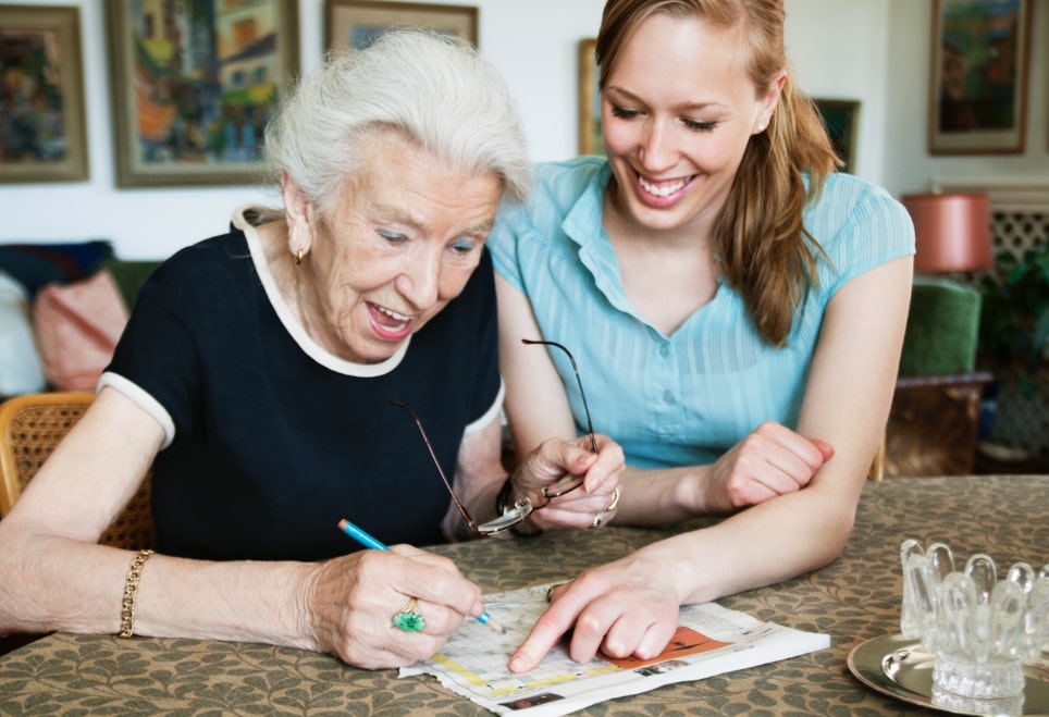 A senior woman with dementia being helped by her in-home care giver